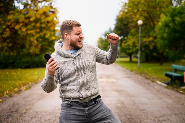 Молодой человек танцует осень в парке