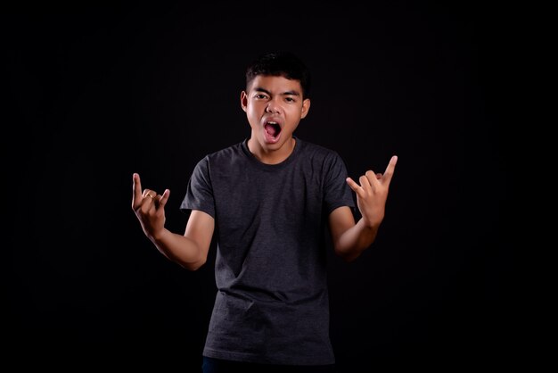 young man in dark t shirt making a rocker gesture