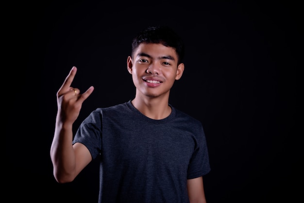 young man in dark t shirt making a rocker gesture