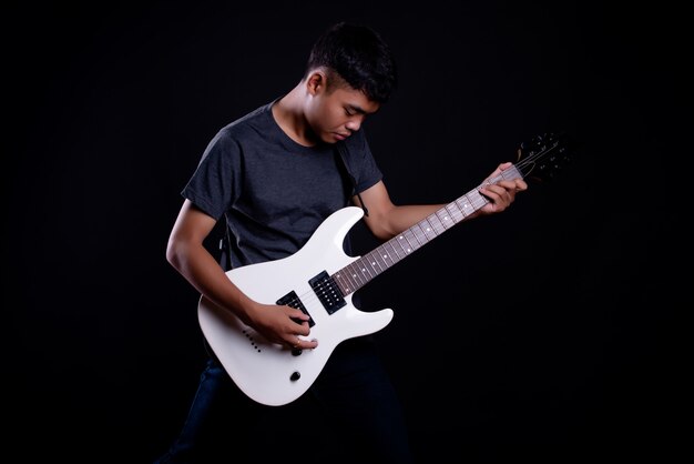 エレクトリックギターと暗いtシャツの若い男