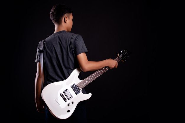 エレクトリックギターと暗いtシャツの若い男