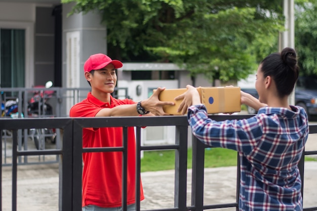 Foto gratuita giovane che consegna il pacchetto al cliente a casa. consegna