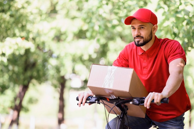 Free photo young man delivering parcel on a bike