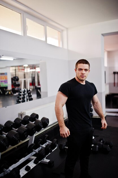 Young man doing exercises and working hard in gym and enjoying his training process