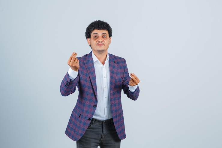 मुफ़्त फोटो young man doing money gesture in shirt, jacket, pants and looking hopeful. front view.