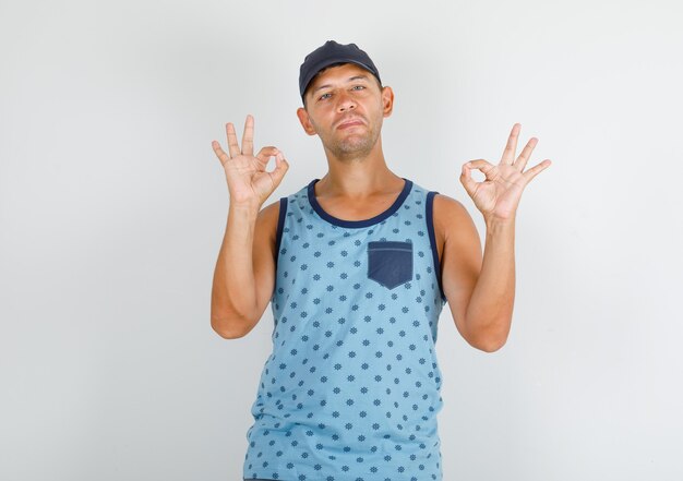 Free photo young man doing ok sign in blue singlet, cap and looking happy