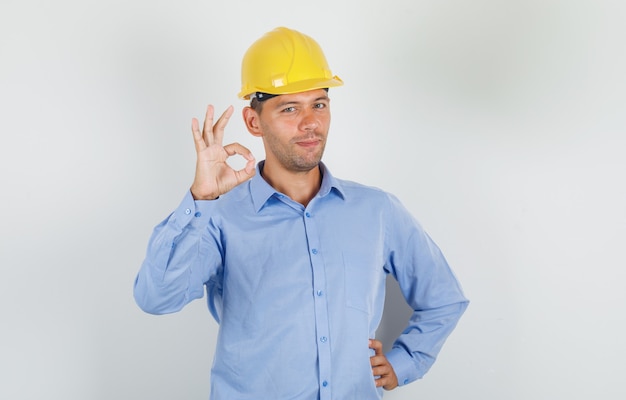 Young man doing ok sign in shirt, helmet and looking happy
