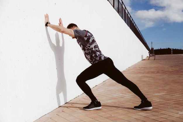 Young man doing standing wall push up