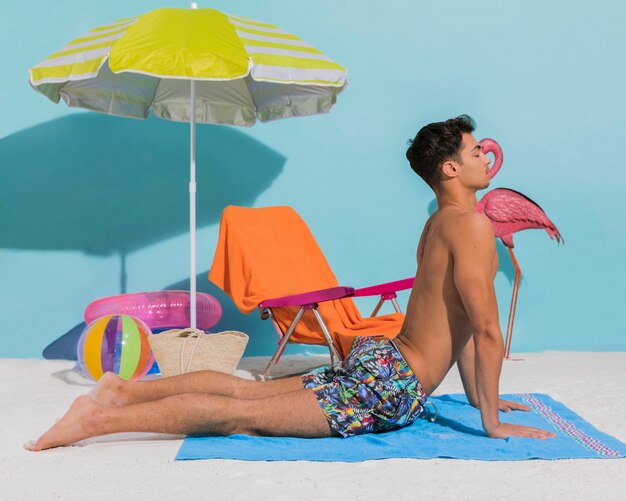 Young man doing yoga on decorative beach