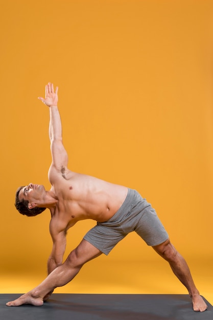 Free photo young man doing yoga on mat