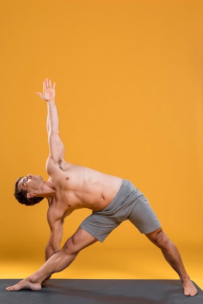 Young man doing yoga on mat