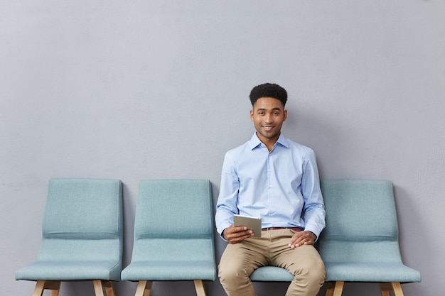 Free photo young man dressed formally sitting in waiting room