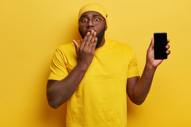 Молодой человек, одетый в желтый, держа телефон