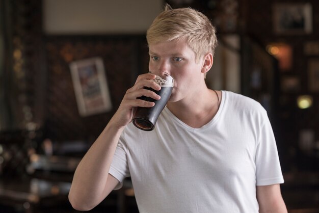 Young man drinking beer in pub