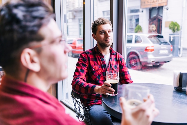 若い男がパブのレストランで彼の友達とビールを飲む