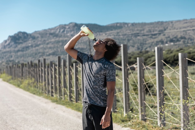 若い男が道路上の水を飲む