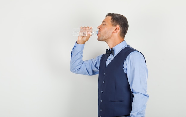 Young man drinking water in suit and looking thirsty.