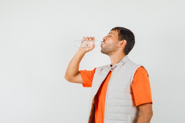 젊은 남자 t- 셔츠, 재킷에 물을 마시는 목 마른, 전면보기.