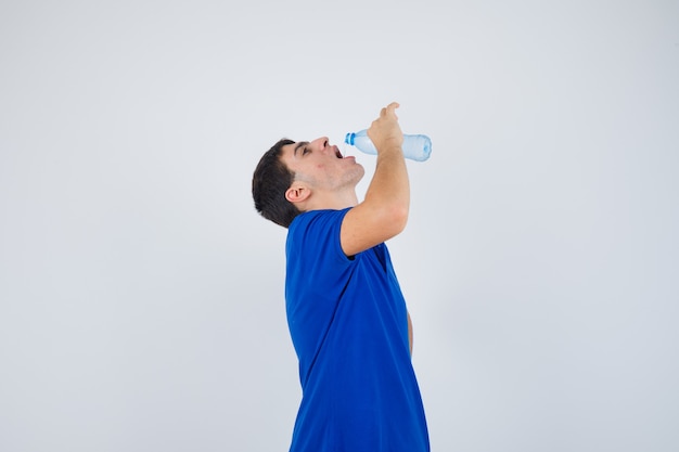 Young man drinking water in t-shirt and looking thirsty