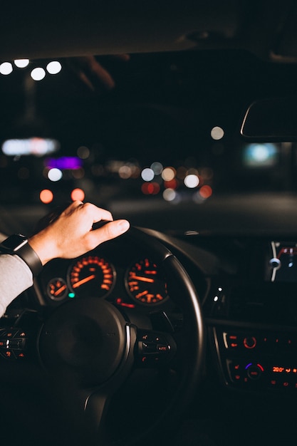 Молодой человек за рулем своего автомобиля в ночное время