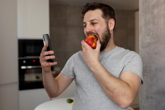 無料写真 若い男が彼のスマートフォンを食べてチェック