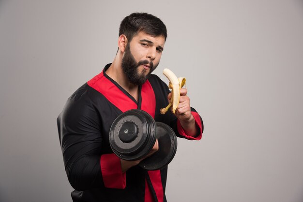 Young man eating a banana and holding a dumbbell .