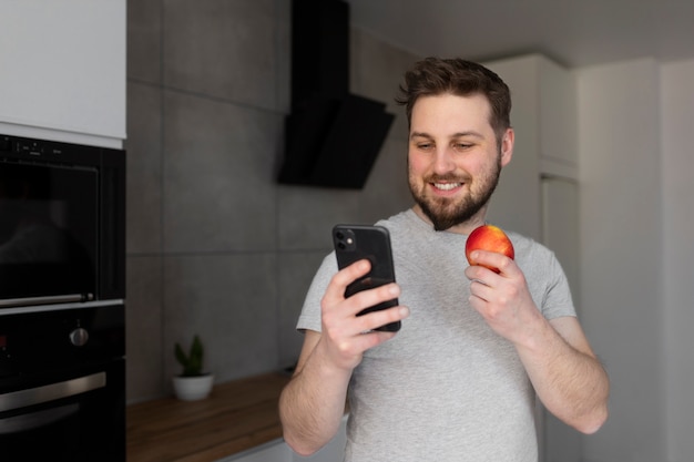 Young man eating and checking his smartphone