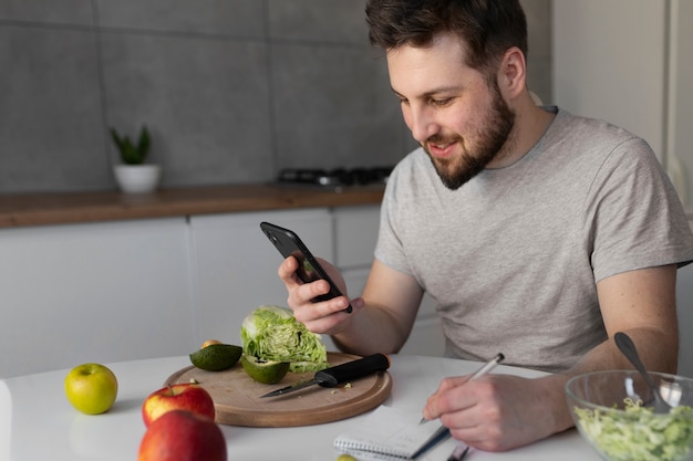 Young man eating and checking his smartphone