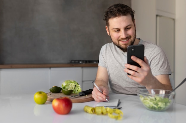 若い男が彼のスマートフォンを食べてチェック