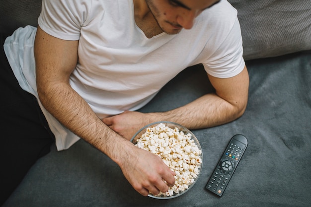 ソファー、ポップコーンを食べる若い男