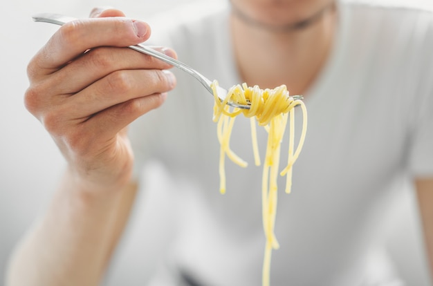 Молодой человек ест вкусные спагетти. Крупный план.
