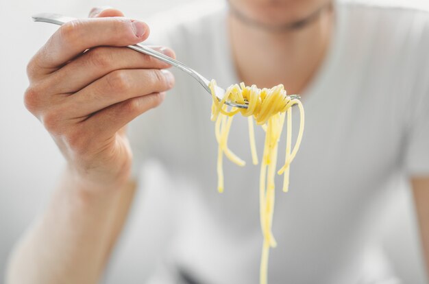 若い男がおいしいスパゲッティを食べます。閉じる。