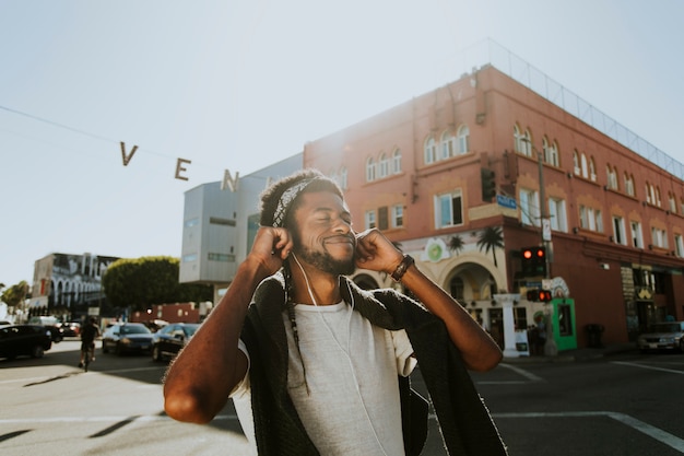 Young man enjoying music while walking in the streets