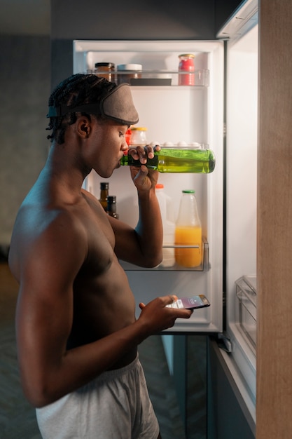 Free photo young man enjoying a snack at home in the middle of the night