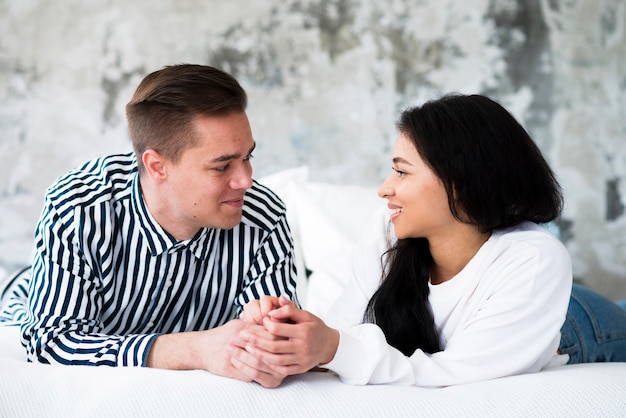 Free photo young man and ethnic woman lying on bed