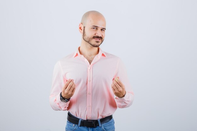 Young man explaining something in pink shirt,jeans front view.