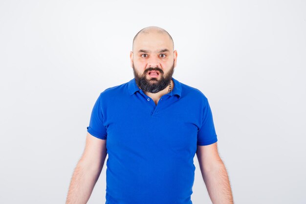 Young man expressing dissatisfaction in blue shirt and looking displeased , front view.