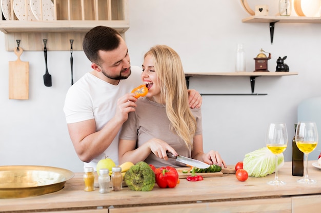 Young man feeding his woman with bell pepper