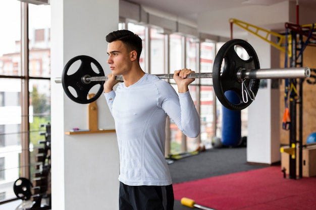 Young man at fitness class lifting weights 