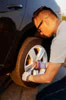 Free photo young man fixing the car wheel