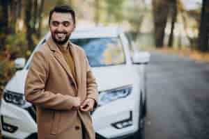 Free photo young man in forest wearing coat by the car