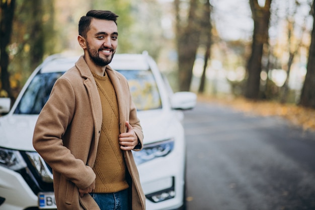 Free photo young man in forest wearing coat by the car