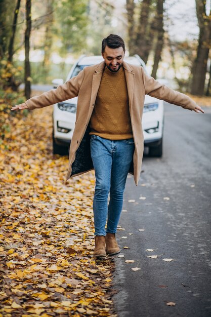 Young man in forest wearing coat by the car