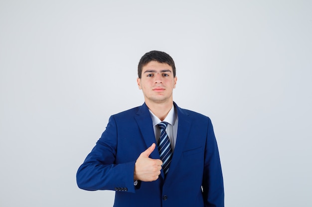 Young man in formal blue suit showing thumb up