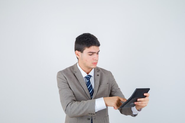 Young man in formal suit holding calculator, doing some operations on it