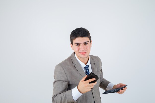 電話と電卓を保持しているフォーマルなスーツの若い男