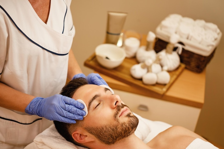 Free Photo young man getting face massage while lying down with eyes closed at spa center