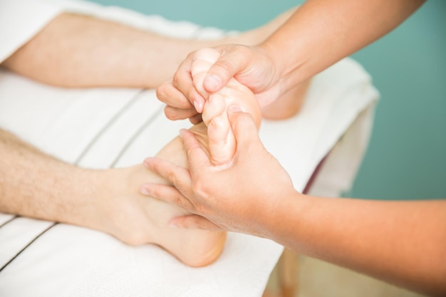 Free photo young man getting a foot massage from a therapist in a health spa. seen up close