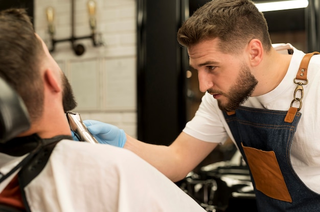 理髪店でひげのスタイルを整える若い男