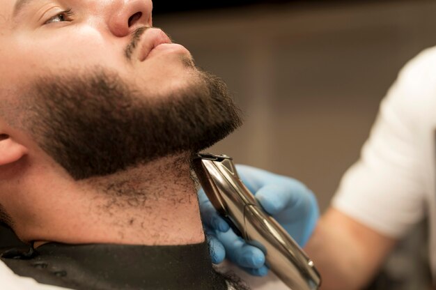 Young man getting his beard styled at the barber